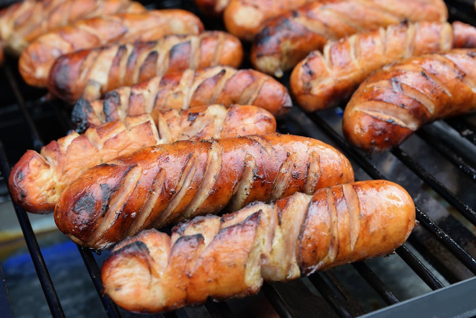 バーベキューグリルでジュージュー焼けるソーセージのクローズアップ。夏のバーベキューにぴったりです。