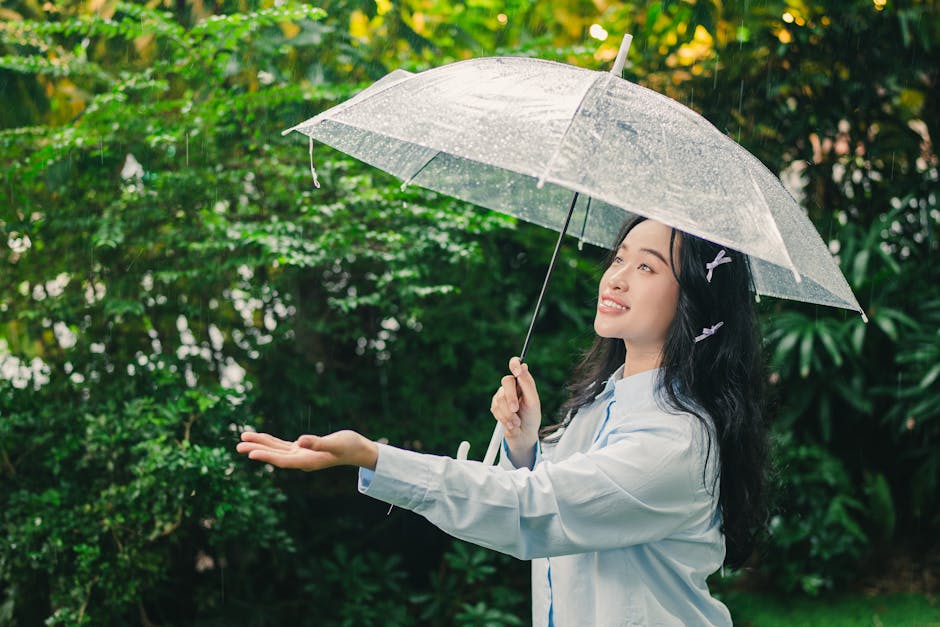 透明な傘の下で雨を楽しむ女性