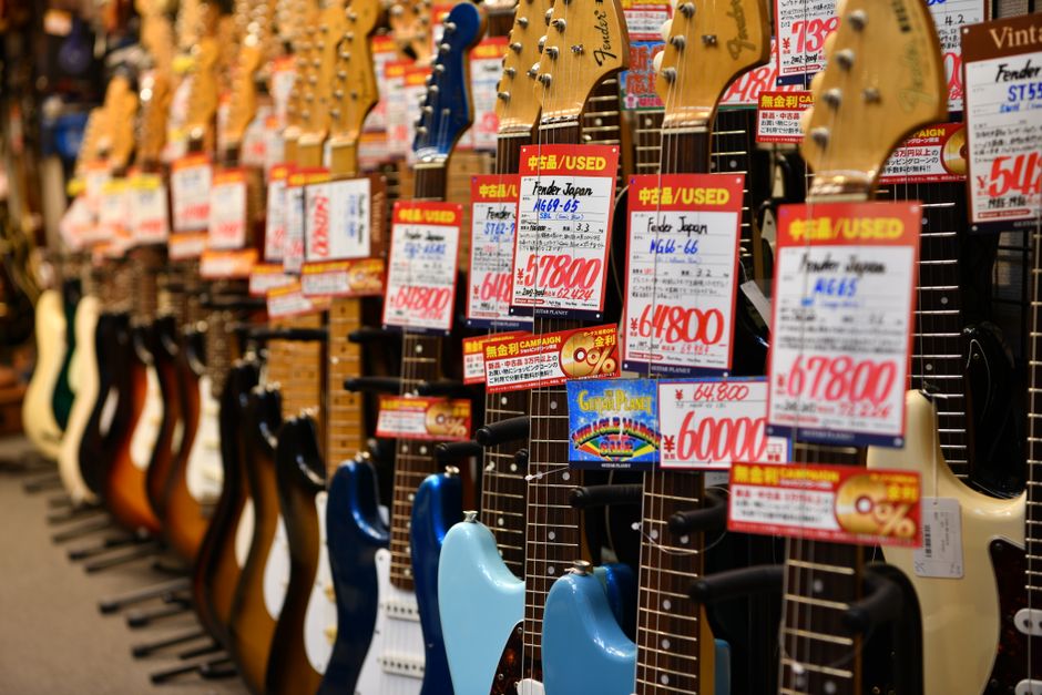 東京のショップでは、中古のフェンダーギターが鮮やかに展示されており、種類と価格が強調されています。